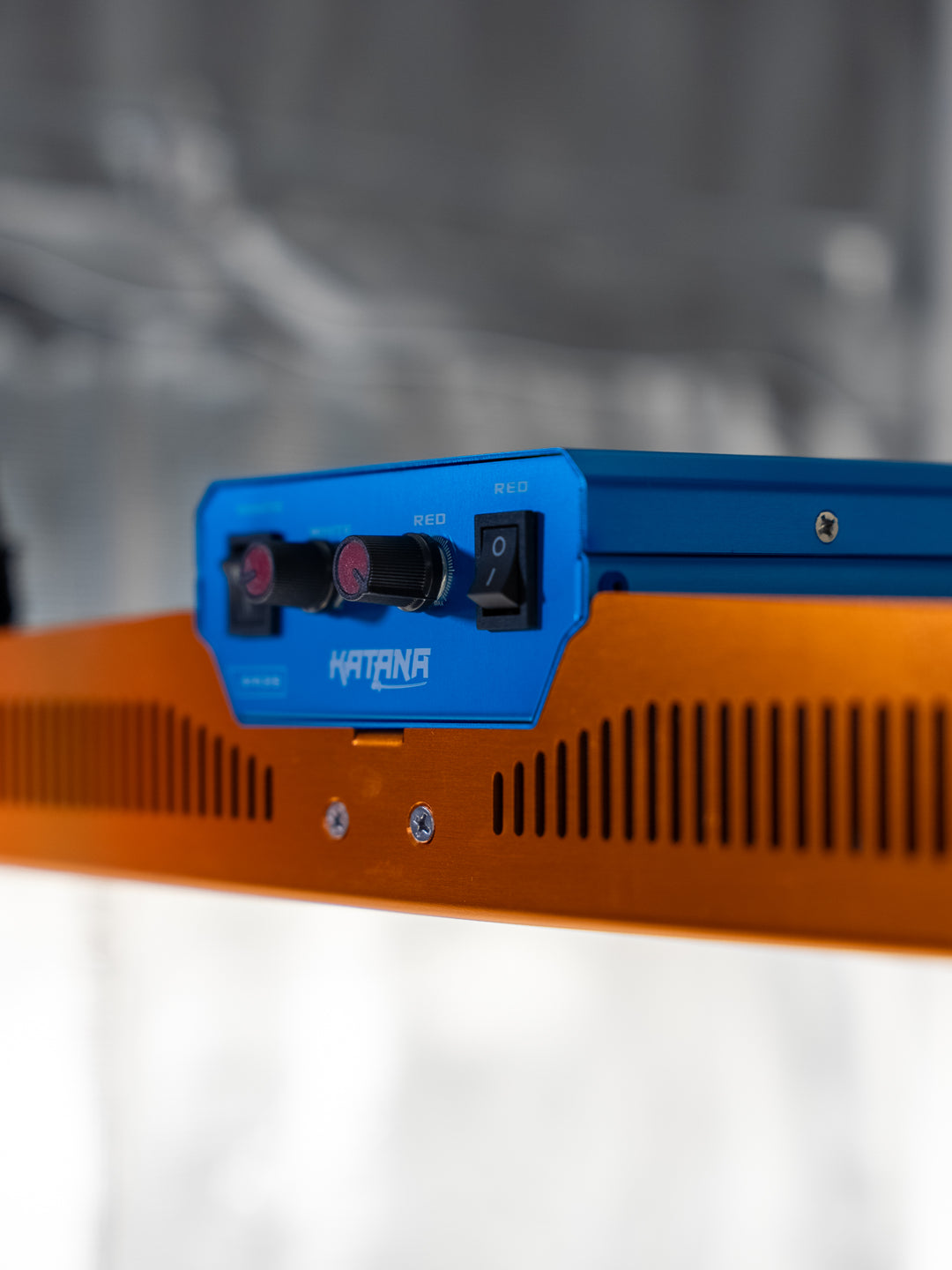 Orange and blue LED electronic device with 'Katana' branding on a blurred background